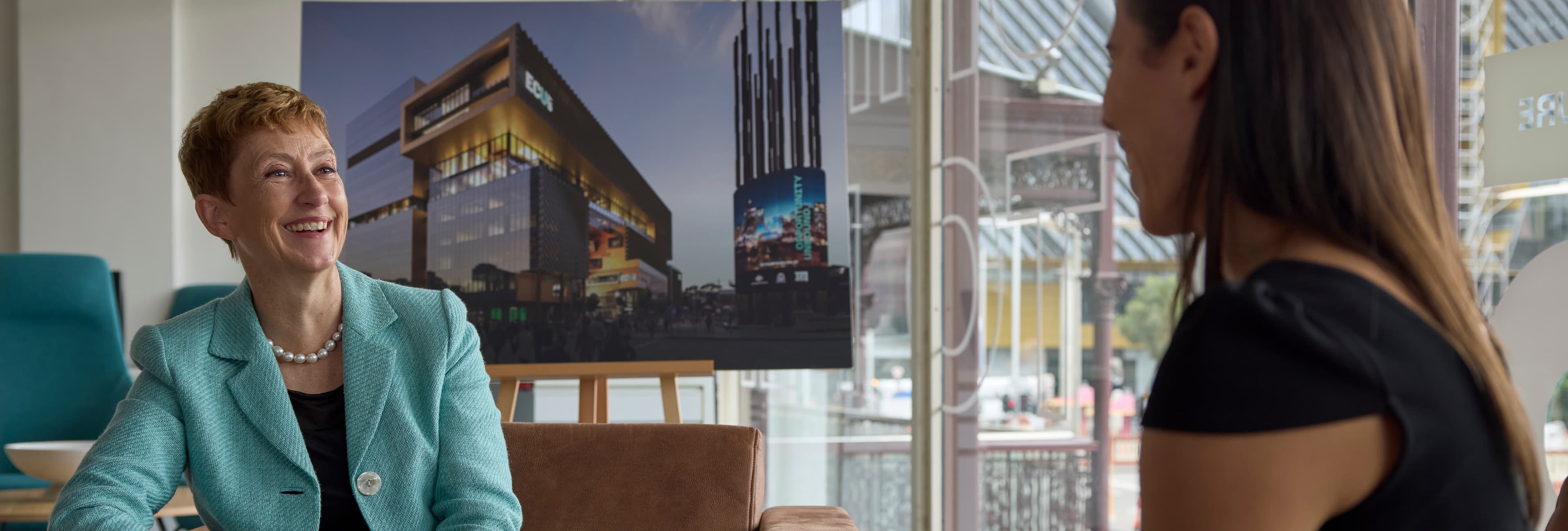 Vice-Chancellor Clare Pollock discussing ECU City campus in front of an image of the campus