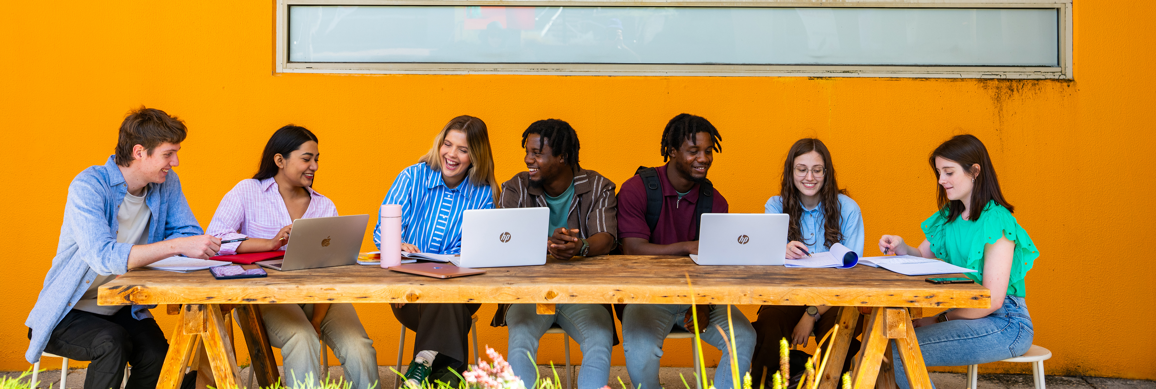 Students groups sitting with laptops on campus